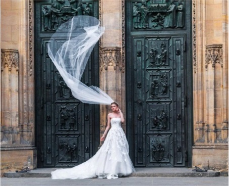 Braut mit wehender Schleppe vor dem Kirchenportal